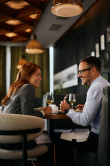 Cheerful coworkers talking during business lunch in restaurant.