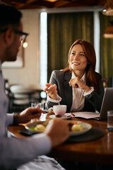 Happy businesswoman having meeting with colleague during lunch in restaurant.