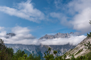 Alpine mountain peaks emerging above a drifting cloud layer