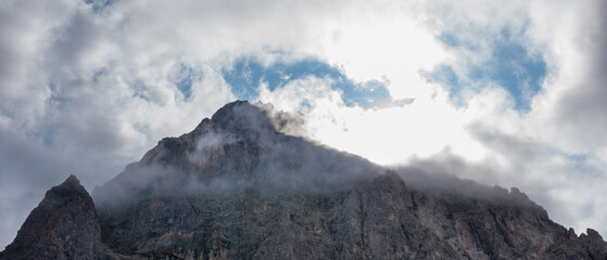 Alpine mountain peaks emerging above a drifting cloud layer