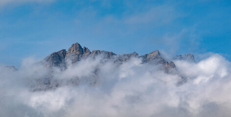Alpine mountain peaks emerging above a drifting cloud layer