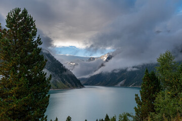 Moody alpine lake Schlegeisspeicher surrounded by dramatic mountain peaks and clouds, turquoise reservoir landscape in the Zillertal Alps, Austria
