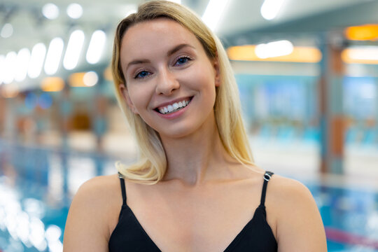 Swim instructor standing poolside in aquatic center