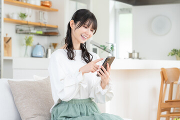 リビングでスマホを見るミドルの女性