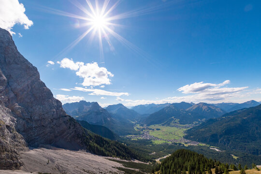 Wide alpine mountain view from the Gamskar overlooking the valley of Ehrwald, rugged rocky slopes, green forests and distant peaks under clear blue sky - Powered by Adobe