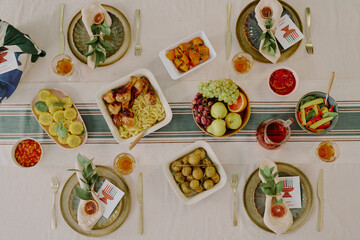 Overhead view showing festive Kwanzaa table setting with assorted traditional dishes, fruits, vegetables, drinks, place settings and decorative elements arranged for celebration
