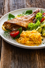 Fried atlantic redfish with boiled potatoes and sauerkraut on wooden table	