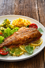 Fried atlantic redfish with boiled potatoes and sauerkraut on wooden table	