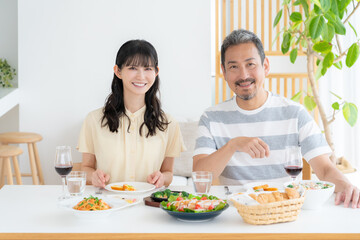 リビングで食事をするミドルの夫婦