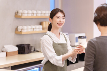 飲み物を客に渡すカフェ店員