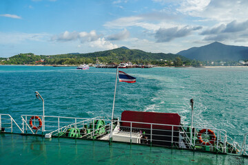 Ferry and Ferry pier near Koh Phangan island in Thailand. The rear of Ferries transport passengers. The beautiful scenery turquoise sea. Big ferry ship with Thai flag turning at the sea and sails.