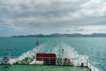 Ferry and Ferry pier near Koh Phangan island in Thailand. The rear of Ferries transport passengers. The beautiful scenery turquoise sea. Big ferry ship with Thai flag turning at the sea and sails.