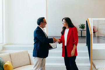 Fototapeta premium Senior management team members shaking hands professionally near a staircase
