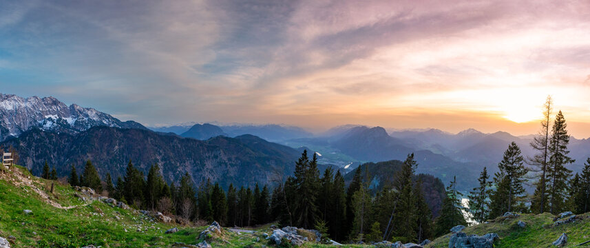 Sunset panorama over the Kaiser Mountains with layered alpine peaks, forested slopes and warm evening light creating a calm and expansive mountain landscape