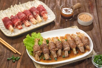 Beef enoki roll is a rolled sheet of beef filled with enoki mushrooms.