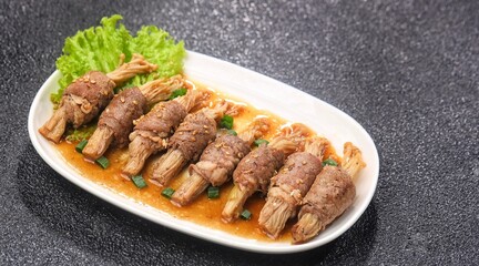 Beef enoki roll is a rolled sheet of beef filled with enoki mushrooms.