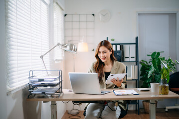 Confident Asian businesswoman multitasking with tablet and laptop in bright office. Perfect for business, consulting, technology, productivity