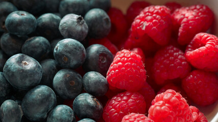 Fresh blueberries and raspberries close up, natural lighting highlighting texture and color