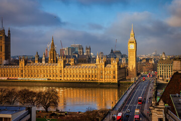 The Westminster Palace and Big Ben clocktower in London, England, during a foggy morning with golden sunlight