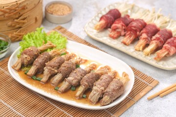 Beef enoki roll is a rolled sheet of beef filled with enoki mushrooms.