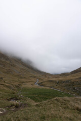 lunar scottish look autumn colored landscape in carpathian valley with low big white clouds ahead