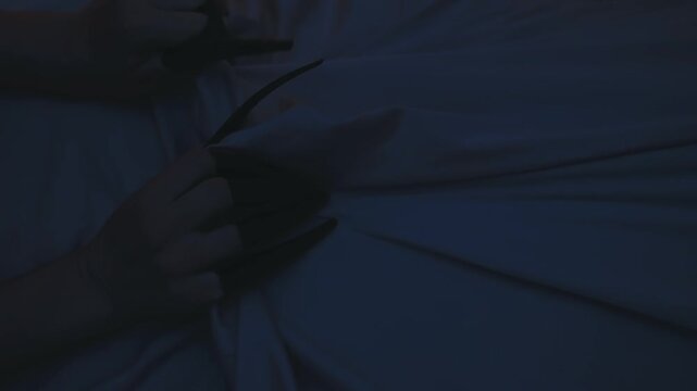 close-up body part scary creepy ghost hands with long black nails pulling blanket off sleeping person, nightmare monster in night dark home room bedroom, spooky fingers evil demon. bad dream in bed