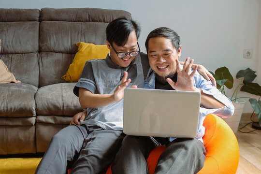 Asian Happy Family Father and Son Using Laptop for Video Call to Mother in Living Room