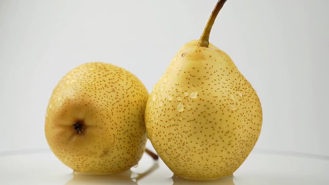 Two Yellow Asian Pears with Brown Speckles and Water Droplets on White Background