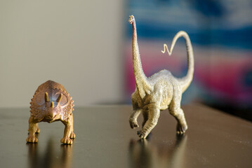 Two figures of Triceratops and Diplodocus dinosaurs on a black table that children like to play with and remind us of the creatures that once lived on Earth