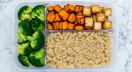 Healthy Vegan Meal Prep Container with Steamed Broccoli Florets, Roasted Sweet Potatoes, and Baked Tofu Cubes on a Marble Background