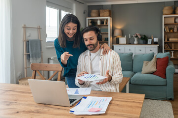 Young couple, freelancer businessman and businesswoman, working at home on laptop computer, testing new innovative technology and online internet tools and their impact on global business.