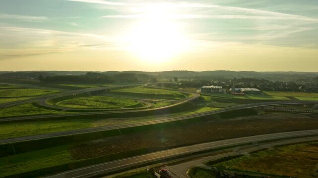 Epic aerial shot of a large highway interchange outside Gdynia, with the bright morning sun directly overhead, illuminating the sweeping curves of the road.
