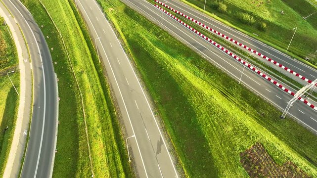 Mid-angle drone shot showcasing the graceful curves and ramps of the S6 expressway, cutting through remarkably lush green rolling hills and embankments.