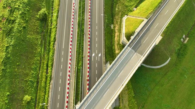 Top-down aerial view capturing the geometric layout of a modern highway overpass and the lanes of the S6 expressway, bordered by red and white safety barriers.