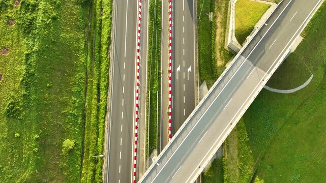 Geometric top-down aerial view of a white van driving under a highway overpass on the S6, highlighting the lines, geometry, and safety barriers