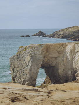 View of a natural arch Arche De Port Blanc Roche Perc&Atilde;&copy;e carved by the ocean's relentless embrace, standing as a sentinel against the turquoise waters, Saint-Pierre-Quiberon, Brittany, France.