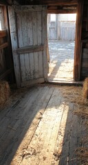 Obraz premium Sunlight streams through an open weathered wooden door into a rustic barn interior.