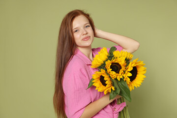 Naklejka premium Teenage girl with bouquet of beautiful sunflowers on green background