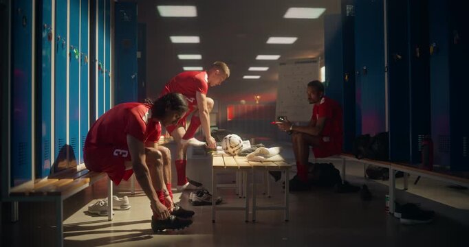 Professional Soccer Team Members Preparing in Locker Room Before the Match. Diverse Group of Players in Red Uniform Lace Up Cleats and Focus Mentally on the Upcoming Game - Powered by Adobe