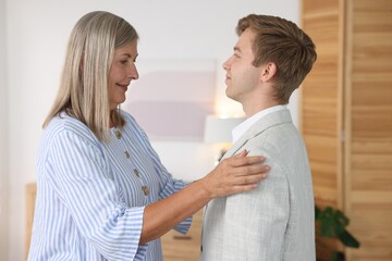 Fototapeta premium Smiling mother taking care of her son at home. Family bonding