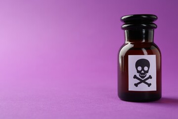 Bottle of poison with warning sign on purple background, closeup. Space for text