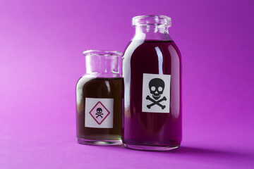Bottles of poison with warning signs on purple background, closeup