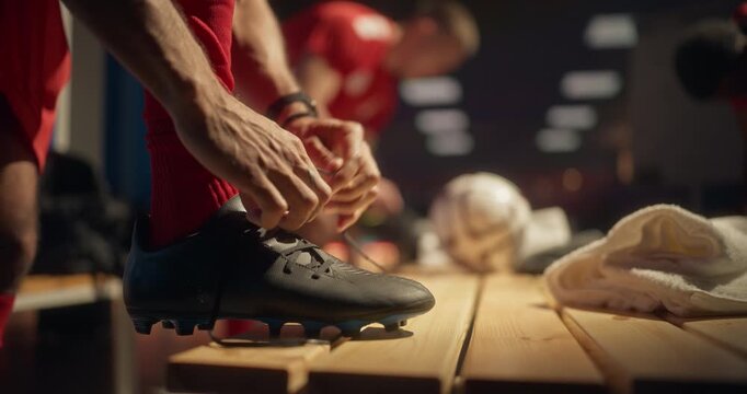 Close Up Footage of Player's Hands Pulling the Laces Tight on a Pair of Black Soccer Cleats. Stadium Locker Room Filled with Team Spirit as Football Players Get Ready for Kickoff
