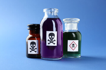Bottles of poison with warning signs on light blue background, closeup