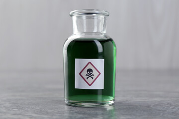 Bottle of poison with warning sign on gray table