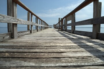 Obraz premium Wooden pier extending into calm water under cloudy sky