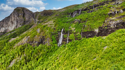 A mountain with a lush green hillside and a waterfall © Kate