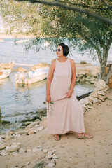 A woman in a long dress walks along the coast, boho style