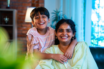 Indian Mother and child embrace affectionately on sofa showing love and care in family bonding