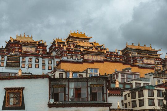 View of the majestic Songzanlin Monastery cascading down the hillside, its golden roofs gleaming against the muted sky, in Di Qing Zang Zu Zi Zhi Zhou, Yun Nan Sheng, China.